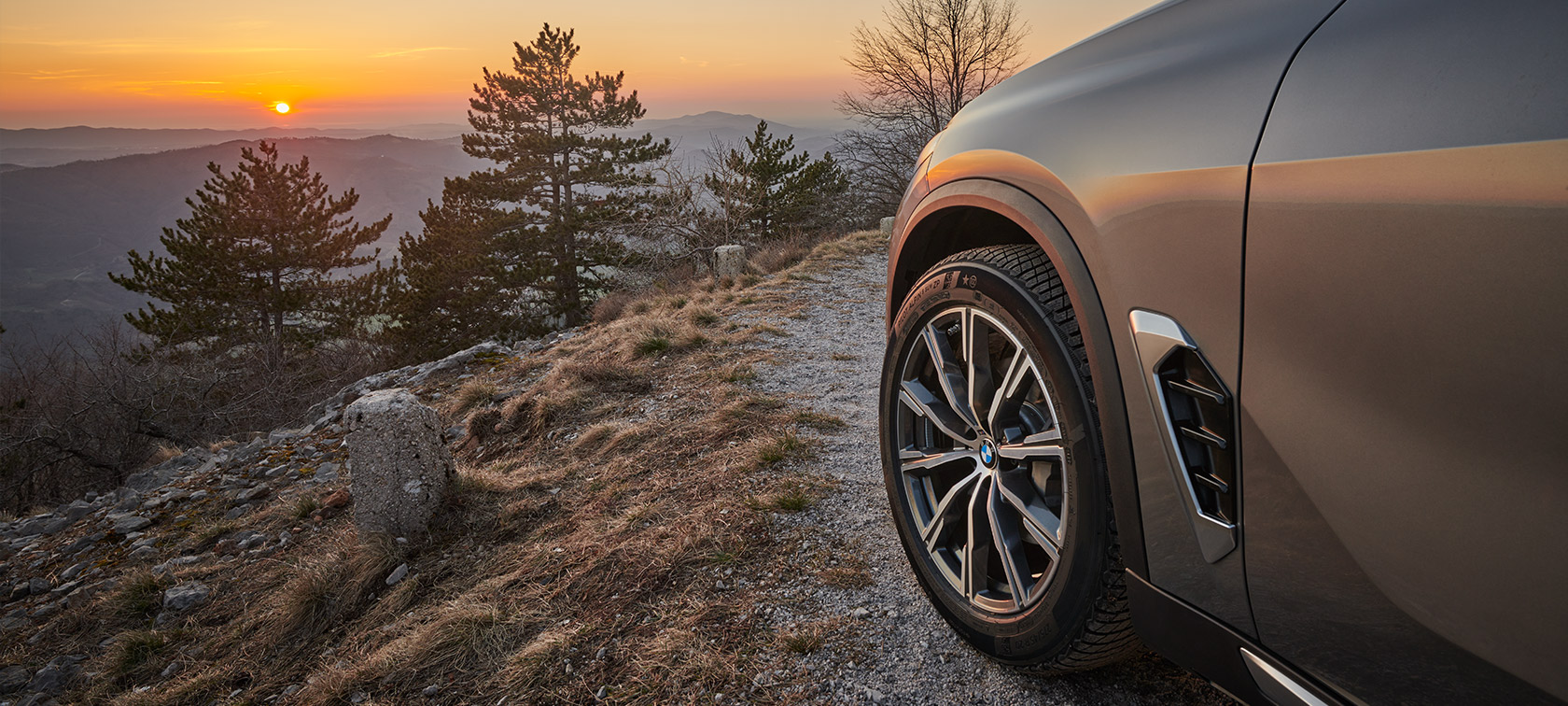 Jantes d'origine BMW sur la BMW X5 (G05 LCI) sur un chemin de gravier à flanc de montagne au coucher du soleil